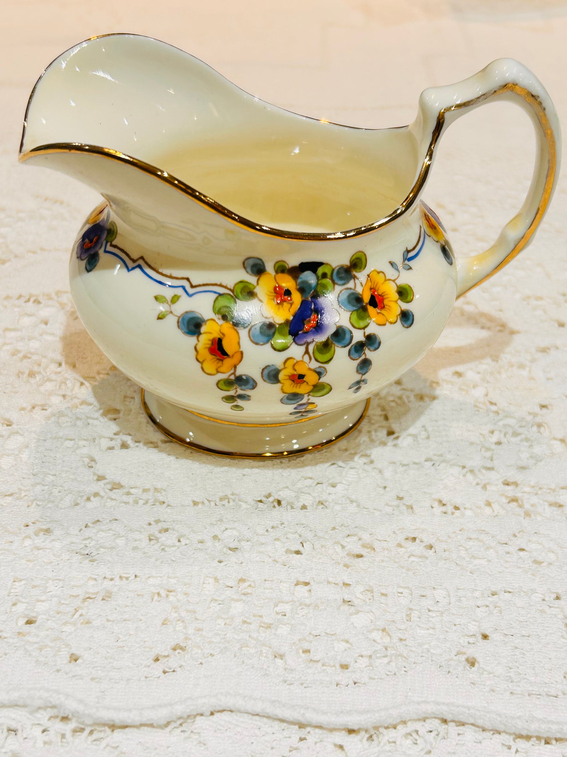 Paragon China.  A Vintage Milk Jug  for Afternoon Tea.  Made in England circa 1930.  Cream  base colour decorated with pretty painted yellow and purple flower sprays   Maker stamp on the base.  Size Medium.